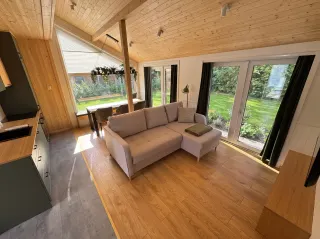 Evergreen Wohnraum mit grauem Sofa, Essbereich und Küchenzeile.