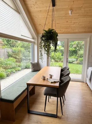 Evergreen Essbereich mit Holztisch, drei Stühlen und Fensterbank.