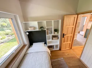 Evergreen Zimmer mit Einzelbett, weißem Regal und Fenster.