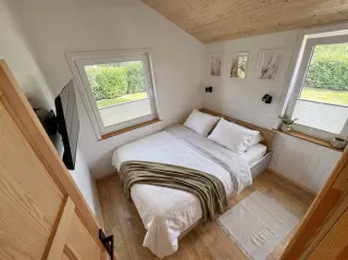 Evergreen Schlafzimmer mit Doppelbett, zwei Fenstern und Holzdecke.