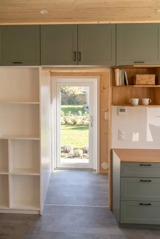 Evergreen Durchgang mit Regal, Küchenschränken und verglaster Außentür.