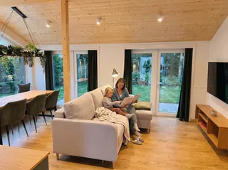 Mutter liest ihrem Kind auf dem Sofa im Evergreen bei warmem Abendlicht aus einem Buch vor