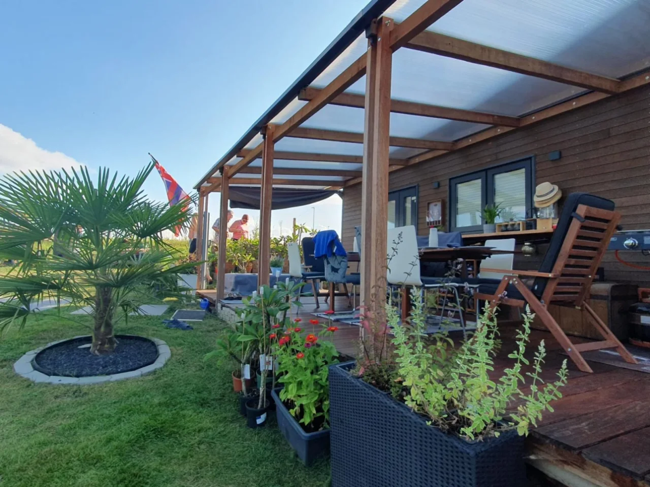 Überdachte Holzterrasse mit Pflanzen und Sitzplätzen