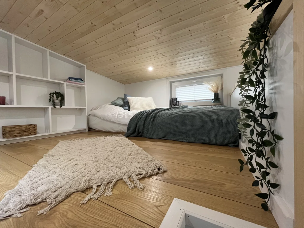 Ruhiges Schlafzimmer mit grünem Bett und hellen Schränken